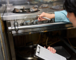 A man checking a gas stove at a restaurant